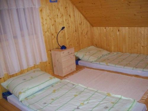 Duas camas num quarto com paredes de madeira em Ferienhaus in Balatonfkajár mit Grill, Garten und Terrasse em Balatonfőkajár