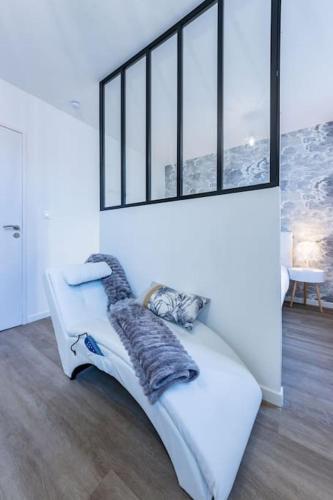 - un canapé blanc dans une chambre avec fenêtres dans l'établissement Le Cocon Agenais - Appart'Hotel SPA - Clim - Melina & Alfred, à Agen