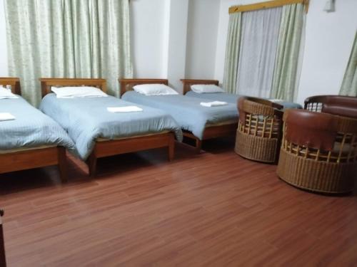 three beds in a room with wooden floors at Crossroad in Shillong