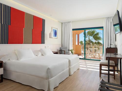 a bedroom with a large white bed and a patio at H10 Playa Esmeralda - Adults Only in Costa Calma