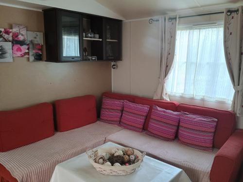 a living room with a red couch with a basket at Mobil-home issis tout confort in Hyères