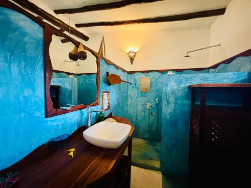 a blue bathroom with a toilet on a wooden counter at Mafía Island Lodge in Utende
