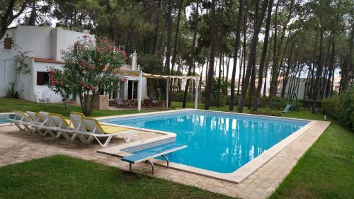 una piscina con 2 sillas y una casa en Villapinheiros, en Vilamoura