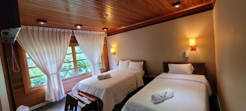 2 camas en una habitación con ventana en Hotel Heidinger en Oxapampa