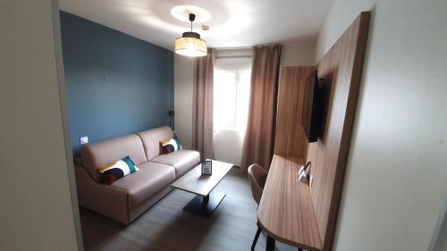 a living room with a couch and a television at Logis Hôtel - Les Pasteliers in Lavaur