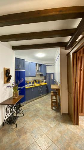 a large kitchen with blue cabinets and a table at “La Carpintería” in Prado del Rey