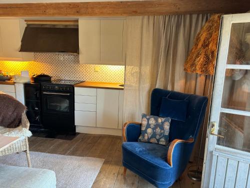 a kitchen with a blue chair and a stove at Cabin retreat in the archipelago in Djurhamn