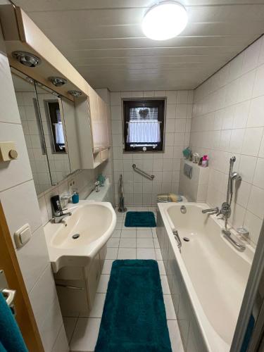 a bathroom with a tub and a sink and a tub and a mirror at Ferienwohnung Emma in Steinwiesen