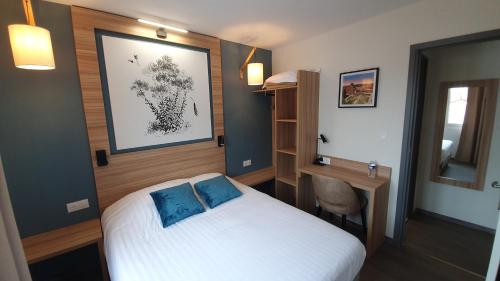 a bedroom with a white bed with blue pillows at Logis Hôtel - Les Pasteliers in Lavaur