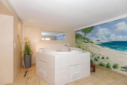 a bathroom with a tub and a painting of the beach at Ferienhaus Sonne & Meer für 7 Personen mit Sauna und Whirpool in Kühlungsborn