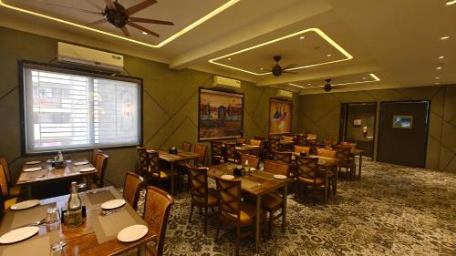a restaurant with tables and chairs in a room at Hotel The Excellency in Surat