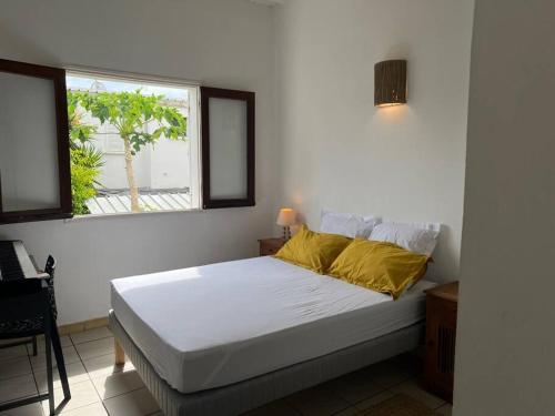 um quarto branco com uma cama e uma janela em Les zoizeaux - T2 à 100m de la plage em Saint-Gilles-les-Bains