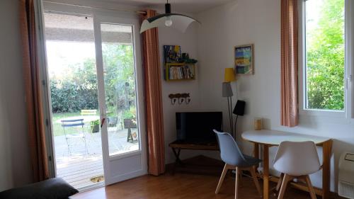 ein Wohnzimmer mit einem Tisch, Stühlen und einem Fenster in der Unterkunft Appartement de plein pied Toulouse Nord in Castelginest