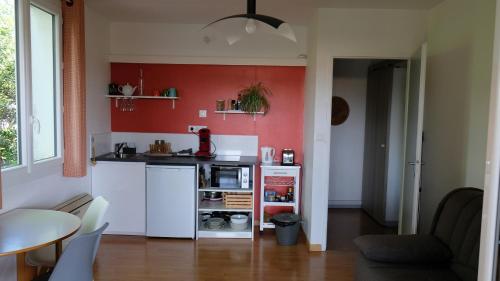 une petite cuisine avec un mur d'accent rouge dans l'établissement Appartement de plein pied Toulouse Nord, à Castelginest