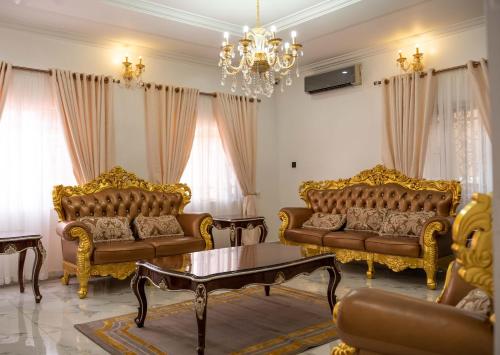 a living room with gold furniture and a chandelier at Duplex16 in Enugu