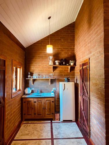 a kitchen with a refrigerator and a brick wall at Chale com hidro na Serra da Mantiqueira in Sapucaí-Mirim