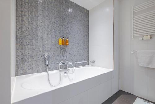 a bathroom with a tub with three bottles on the wall at Crowne Plaza Amsterdam - South by IHG in Amsterdam
