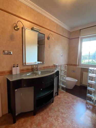 a bathroom with a sink and a mirror and a tub at Chalet con Piscina Privada in Santander