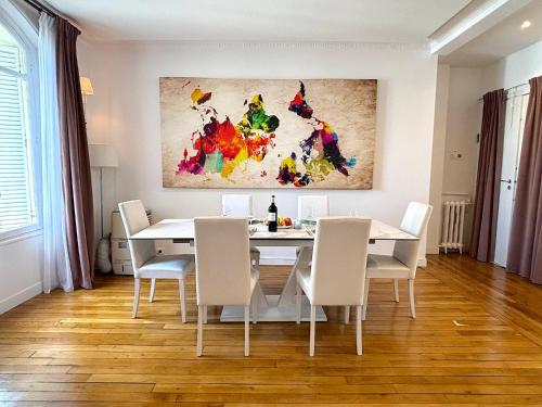 une salle à manger avec une table et des chaises blanches dans l'établissement L'appartement Passy, à Paris