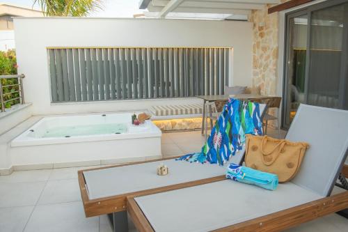 um quarto com uma banheira e um banco com uma bolsa em Hotel Golden Sun em Nea Mesangala