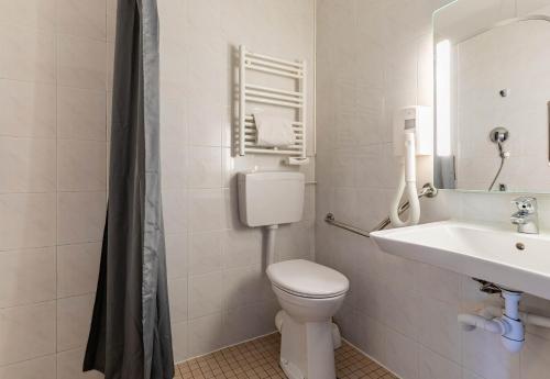 a white bathroom with a toilet and a sink at B&B HOTEL Colmar Lumière in Colmar