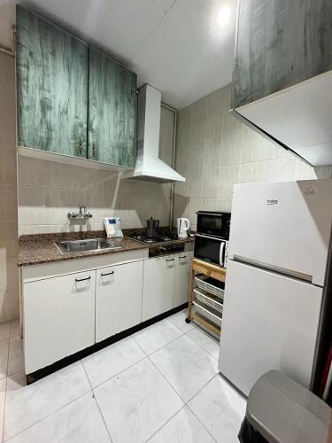 a kitchen with white cabinets and a white refrigerator at SunFlower Apartment in Barcelona