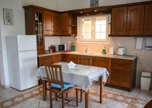 PotamósにあるThalassi Apartment Alykes Potamos Corfuのキッチン(テーブル、白い冷蔵庫付)