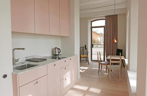 a kitchen with white cabinets and a dining room at Kleines Fährhaus in Ulsnis