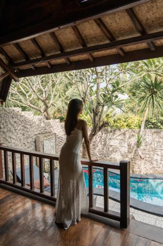 a woman in a white dress standing on a railing at Yoki's Bungalow in Kuta Lombok