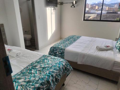 two beds in a hotel room with a window at HOTEL CALIFORNIA in Pitalito