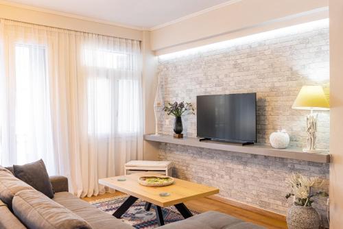 a living room with a couch and a tv on a brick wall at Pythagorio Blue Street Apartment with Balcony in Pythagoreio