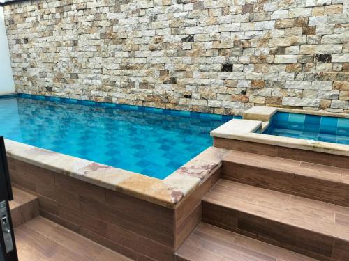 a swimming pool with a stone wall and blue water at HOTEL CALIFORNIA in Pitalito