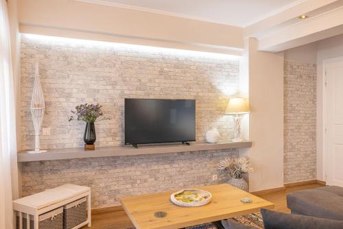 a living room with a tv on a brick wall at Pythagorio Blue Street Apartment with Balcony in Pythagoreio