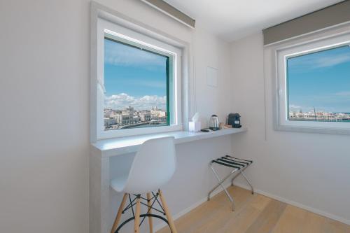 a white room with two windows and a stool at La Finestrella in Bari