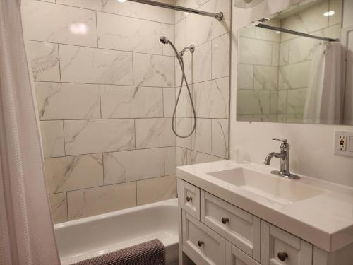La salle de bains blanche est pourvue d'un lavabo et d'une douche. dans l'établissement Auberge les Etchemins, à Sainte-Germaine-du-Lac-Etchemin