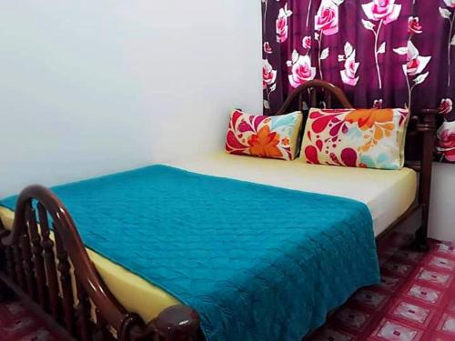 een bed met een blauwe deken en kussens erop bij RANIA HOMESTAY WAKAF CHE YEH in Kota Bharu