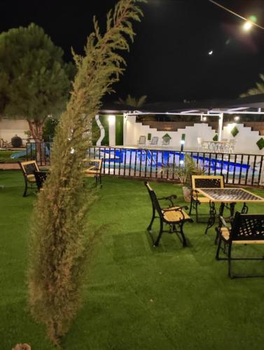 a group of chairs and tables in a yard at night at منتجعات ريفانا in Aţ Ţuwayr