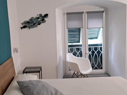 a white bedroom with a white chair and a window at I Profumi del Mare in La Spezia
