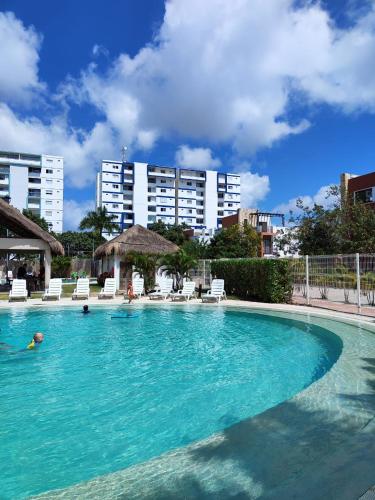 a large swimming pool with chairs and a building at Depa en Cancun con alberca in Cancún