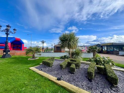 a garden with trees and bushes in the grass at Luxurious caravan in Lyons Holiday Park Rhyl in Meliden