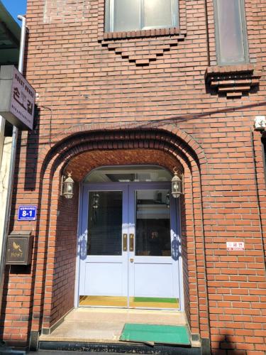 un edificio de ladrillo con una puerta blanca. en Son-Gil Guesthouse, en Jinju