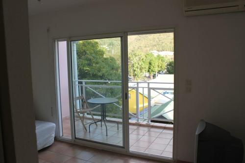 a room with a sliding glass door with a table on a balcony at Location studio vue exceptionnelle proximité mer in Gourbeyre