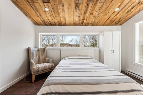 1 dormitorio con 1 cama y 1 silla en Cozy, luminous and charming retreat, en Harrington