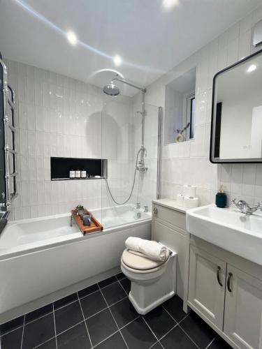 a bathroom with a tub and a toilet and a sink at Cozy and Peaceful Apartment with Terrace in Hackney in London