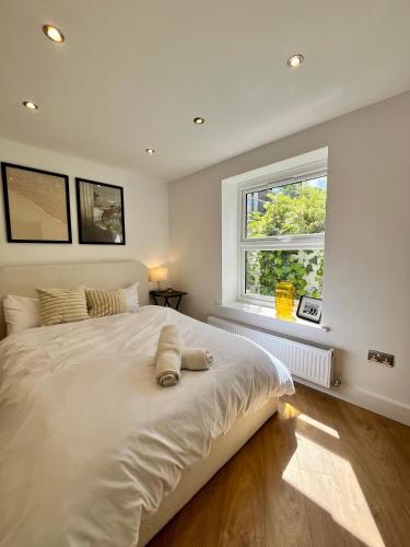 a bedroom with a large white bed with a window at Cozy and Peaceful Apartment with Terrace in Hackney in London