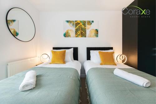 2 letti in una camera con cuscini verdi e gialli di Modern 2 Bedroom Urban Oasis a Kent