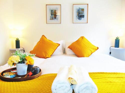 Luxury 2 Bed, 2 Bath Apartment in Central Watford في واتفورد: سرير أبيض مع وسائد صفراء وصينية مع المناشف