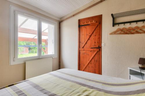 Schlafzimmer mit einem Bett, einem Fenster und einer Tür in der Unterkunft Séjour calme dans une maison avec jardin in Saint-Maixent-sur-Vie