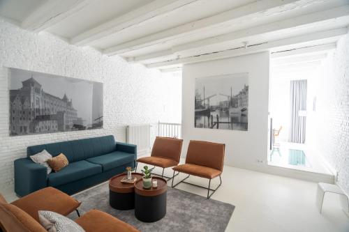 a living room with a blue couch and two chairs at YAYS Amsterdam Salthouse Canal by Numa in Amsterdam