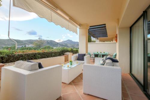 a balcony with white wicker furniture and a view of the mountains at 2-bed apt in Capanes del Golf in Benahavís